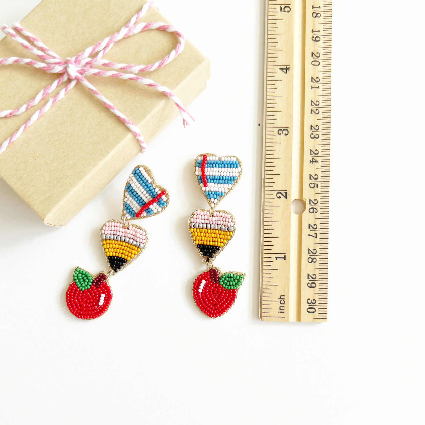 hand beaded school earrings laying next to small gift box and ruler showing they are roughly 2.5 inches long