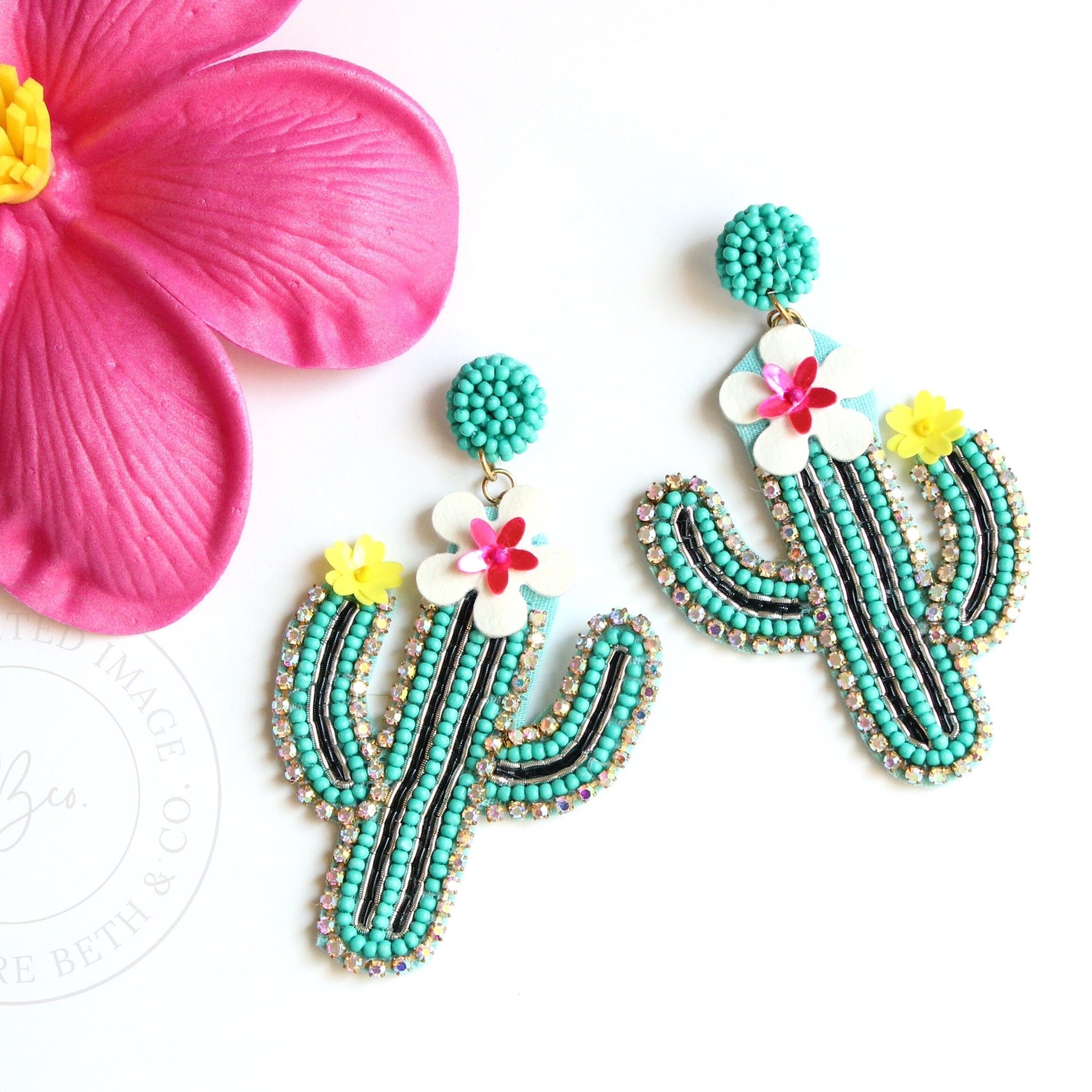 floral cactus beaded earrings on flat surface next to hot pink flower