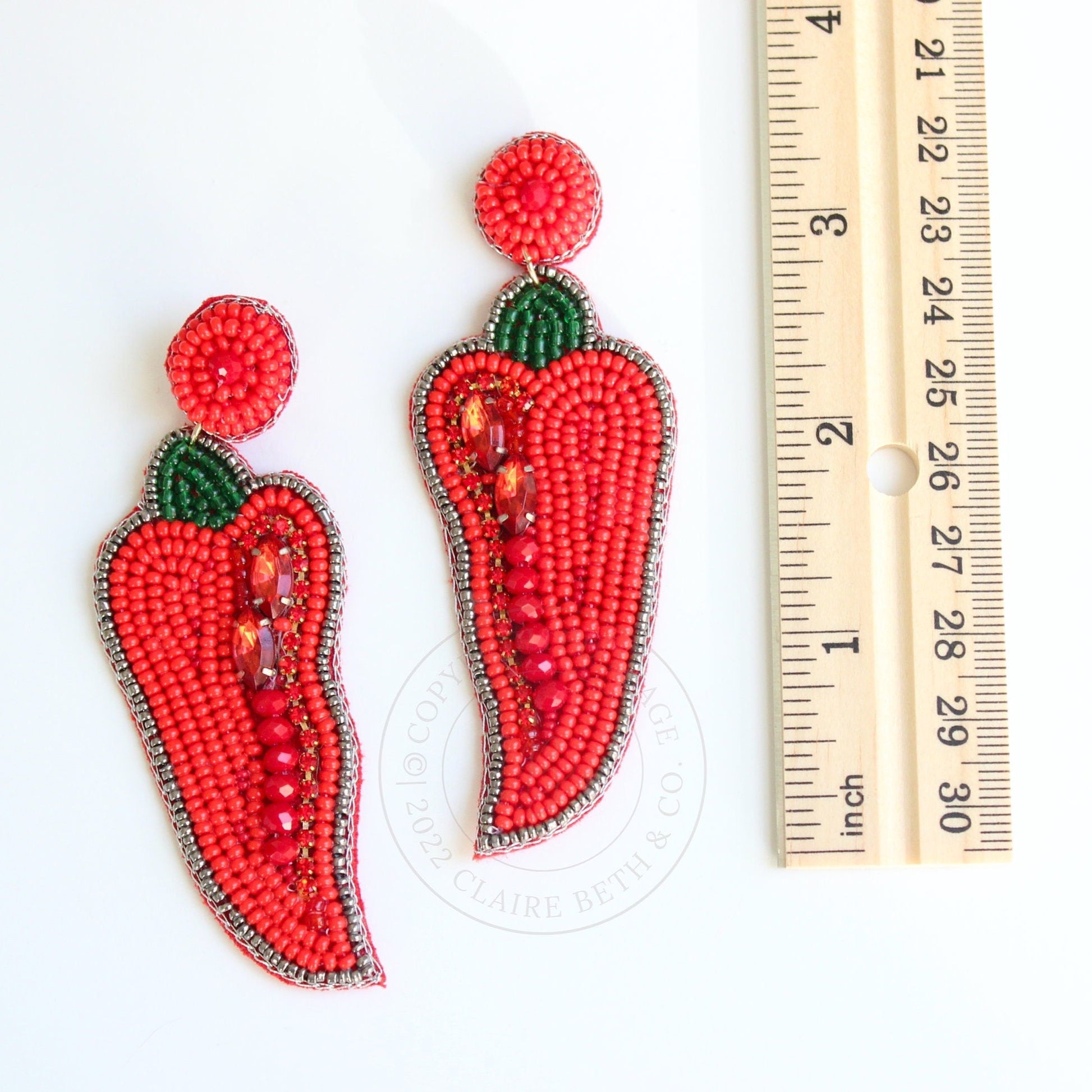 chili pepper beaded earrings next to ruler showing just over 3 inches in length