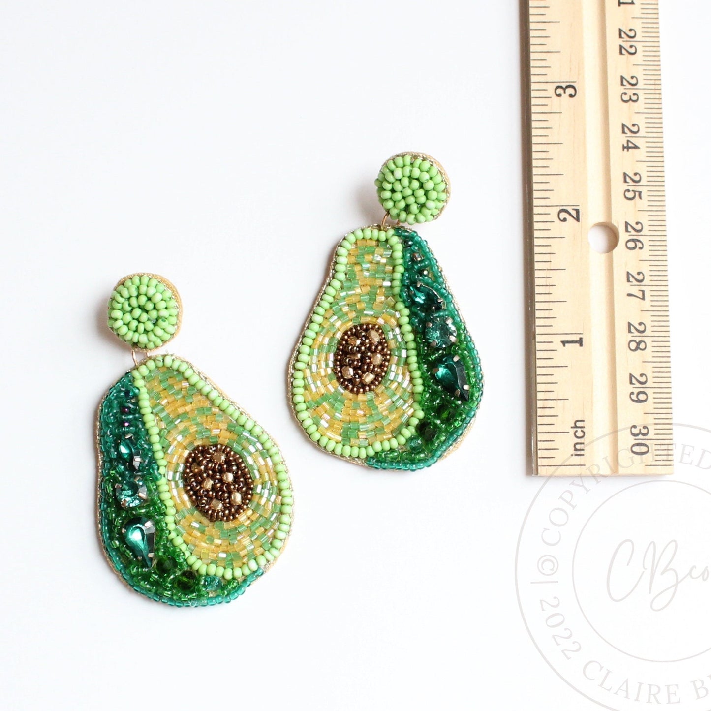 avocado beaded earrings on flat surface next to ruler showing they are approximately 2.5 inches long